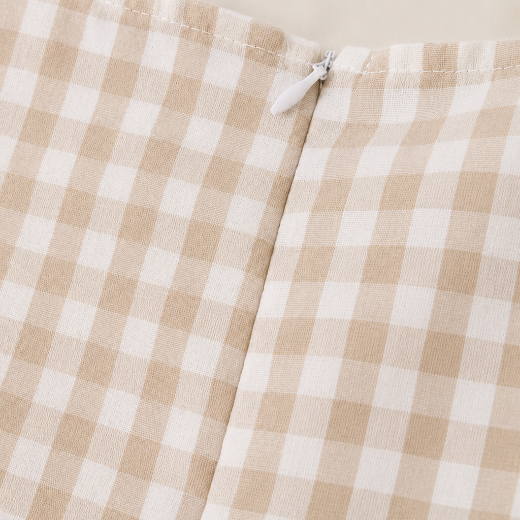 Close-up of a beige and off-white gingham check fabric with a small white zipper pull visible at the top center.