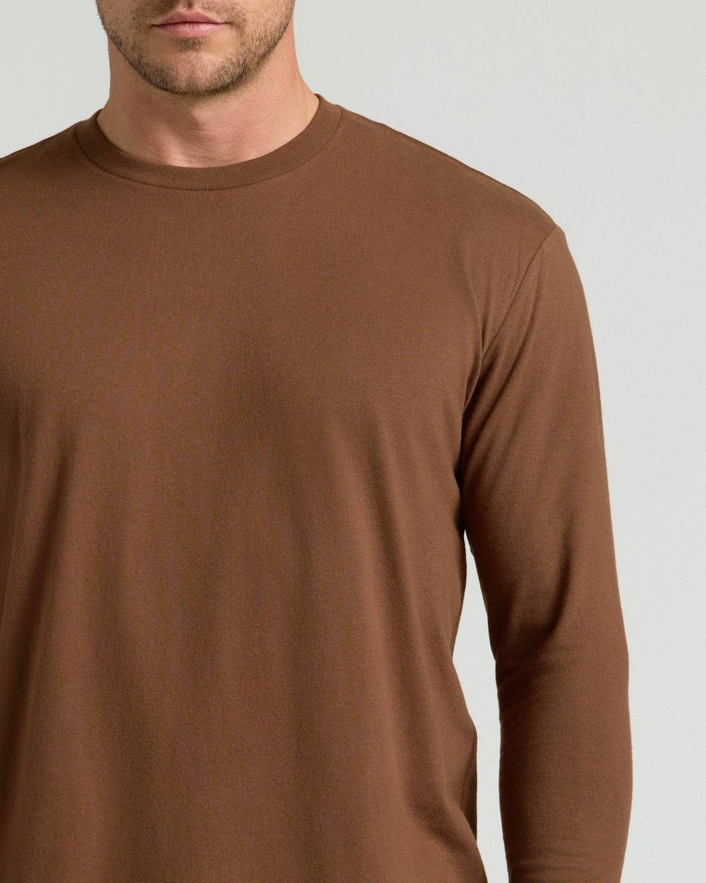 Brown long-sleeve shirt worn by a person on a light gray background