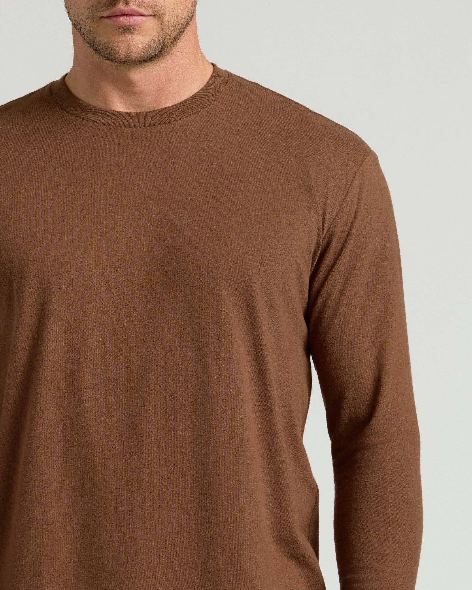 Brown long-sleeve shirt worn by a person on a light gray background