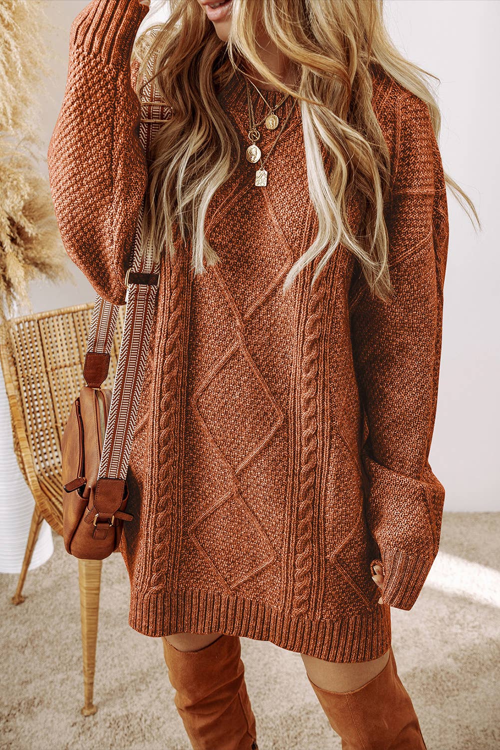 Person wearing a brown cable knit sweater and brown knee-high boots, standing indoors.
