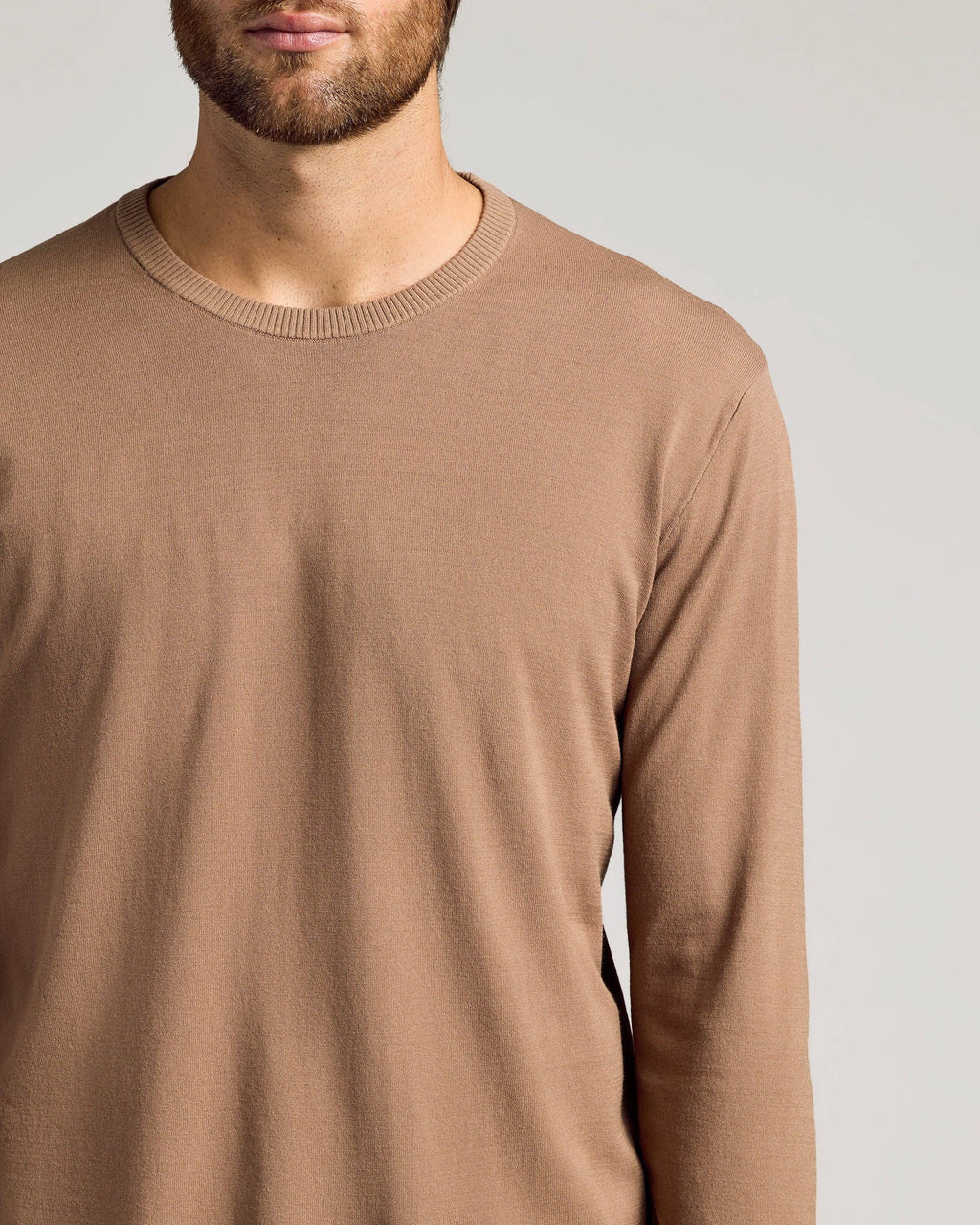 Man wearing a brown long-sleeve shirt against a plain background