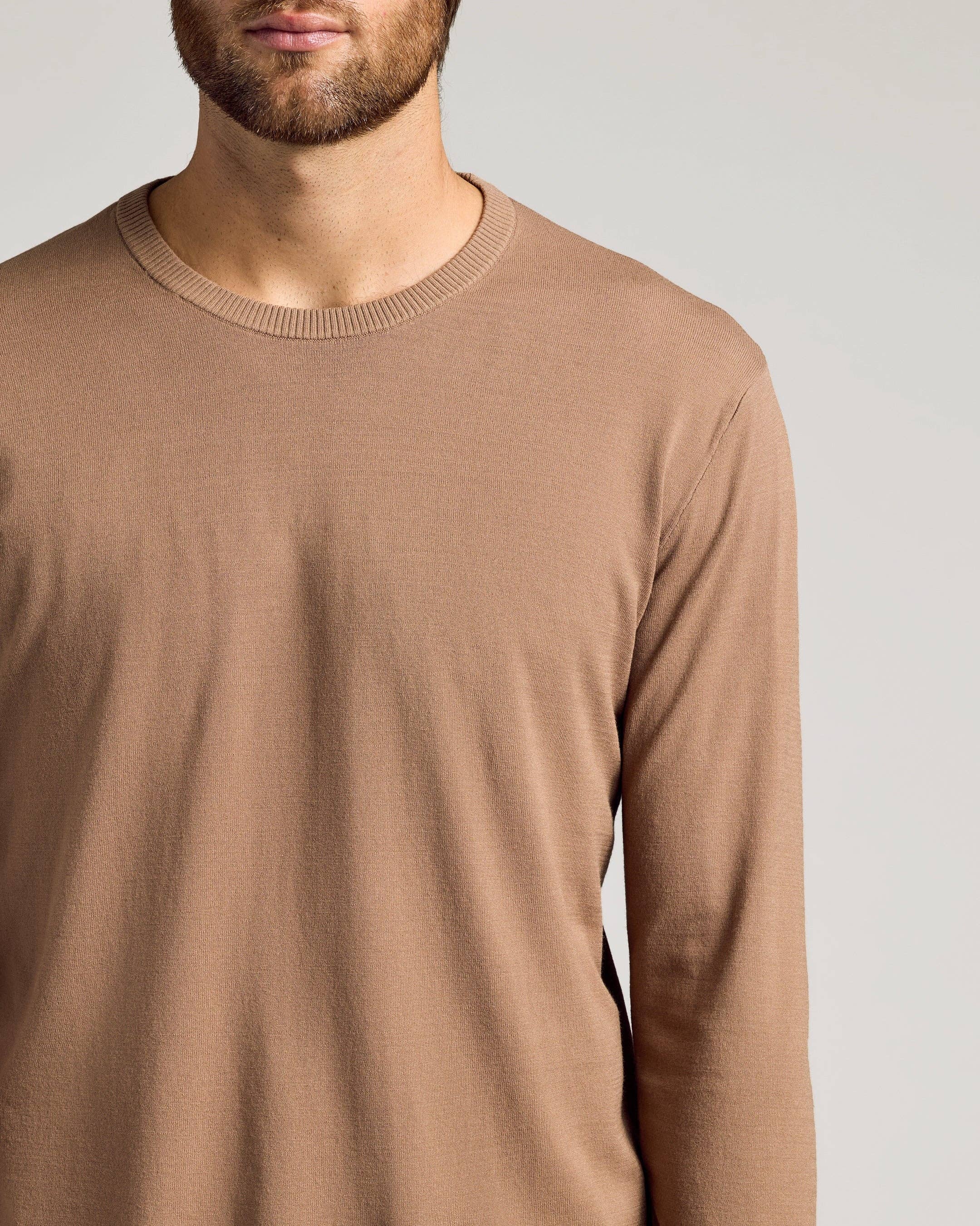 Man wearing a brown long-sleeve shirt against a plain background