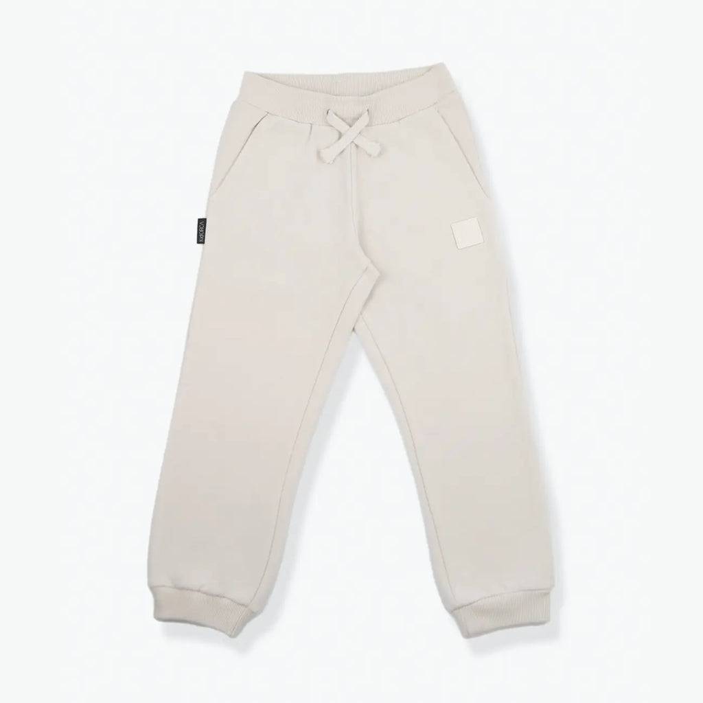 A pair of light beige sweatpants with a drawstring waist and ribbed cuffs, laid flat on a white background.